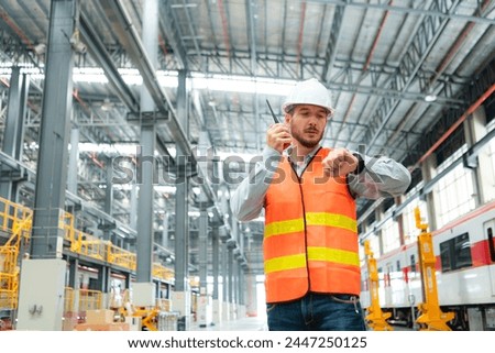Portrait of a young male technician using a walkie talkie working and standing in a skytrain repair station.