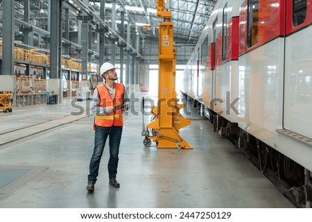 Portrait of a young male technician using a tablet working and standing in a skytrain repair station.