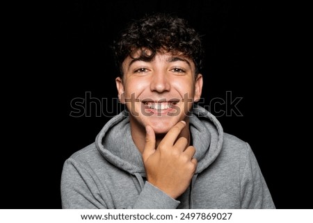 Similar – Portrait of a smiling Caucasian man in his 20s wearing a sweatshirt against a dark background.