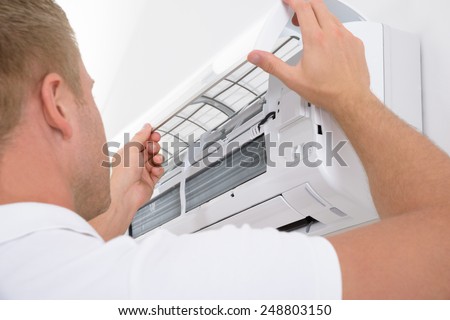 Portrait Of A Young Man Adjusting Air Conditioning System