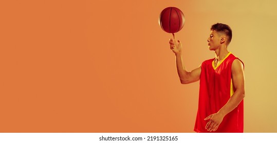 Portrait of young man, basketball player spinning ball on finger isolated over orange studio background in neon light. Concept of healthy lifestyle, professional sport, hobby, power and strength - Powered by Shutterstock