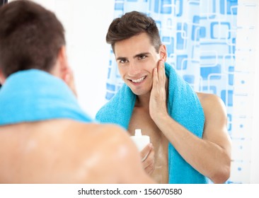 Portrait of a young man in the bathroom applying after shave - Powered by Shutterstock