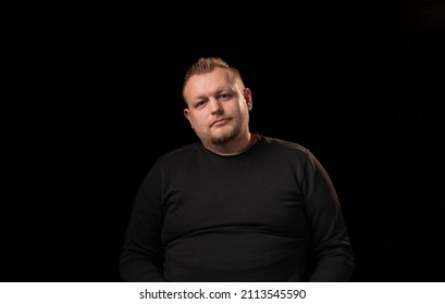 Portrait Of A Young Man With A Beard. Dark Background. A Slightly Overweight Man With A Large Build.