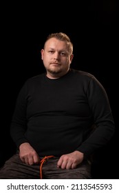 Portrait Of A Young Man With A Beard. Dark Background. A Slightly Overweight Man With A Large Build.