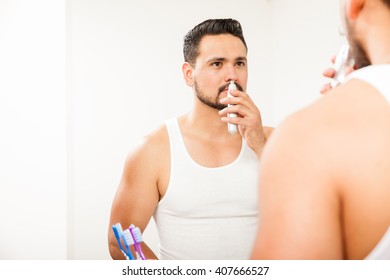 Portrait Of A Young Man With A Beard Trimming Nose Hair While Standing In Front Of A Mirror In The Bathroom