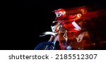 Portrait of young man, biker in full equipment riding motorbike isolated over black studio background with mixed lights. Concept of motosport, speed, action, hobby, competition. Copy space for ad