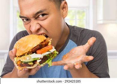 A Portrait Of A Young Man Bite His Big Burger Deliciously