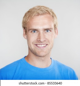 Portrait Of A Young Man With Blond Hair Smiling - Isolated On Light Gray