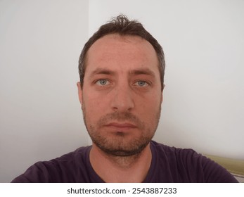 Portrait of a young man with a calm yet intense gaze, symbolizing quiet resilience and introspection, as he looks directly at the camera in a minimalistic, neutral setting. - Powered by Shutterstock