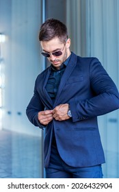 Portrait Of A Young Man In The City Dressed Bussines. Young Sucessful Businesman Is Posing For Photographer Near His Office