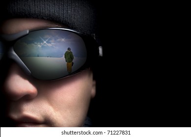 Portrait Of A Young Man Close Up. In The Glasses Reflection The Mountains And Snowboarders