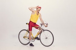 Portrait Of Young Man In Colorful Clothes, Uniform Riding Bike Isolated Over Grey Background. Summertime Drive. Concept Of Sport, Hobby, Work, Active Lifestyle, Retro Fashion. Copy Space For Ad