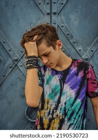 portrait of a young man in a colorful T-shirt and bracelets on his arm next to a metal gate - Shutterstock ID 2190530723