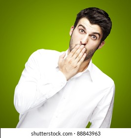 Portrait Of Young Man Covering His Mouth With Hand Over Green