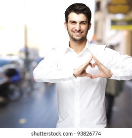 Portrait Of A Young Man Doing A Heart Symbol Against A Street Background