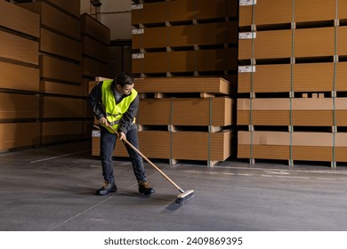 Portrait of young man with Down syndrome sweeping the floor, working in factory, warehouse. Concept of workers with disabilities, support in workplace. - Powered by Shutterstock