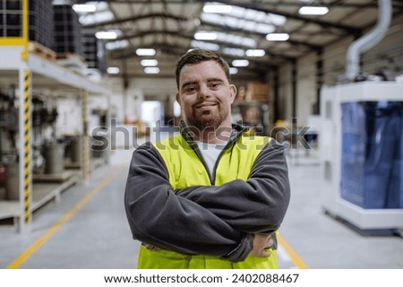 Portrait of young man with Down syndrome working in warehouse. Concept of workers with disabilities, support in workplace.