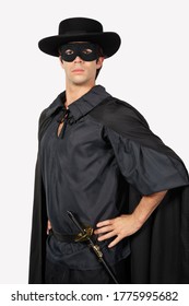 Portrait of young man dressed as Zorro against gray background