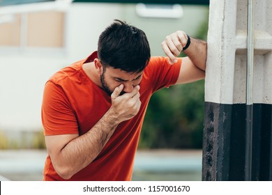 Portrait of young man drunk or sick vomiting outdoors