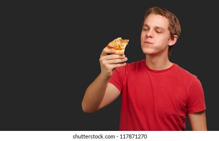 Portrait Of A Young Man Eating Pizza On A Black Background