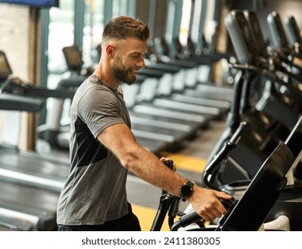 Portrait of a young man exercising on an elliptical trainer in a gym, running using  thereadmill machine equipment, healthy lifestyle and cardio exercise at fitness club concepts - Powered by Shutterstock