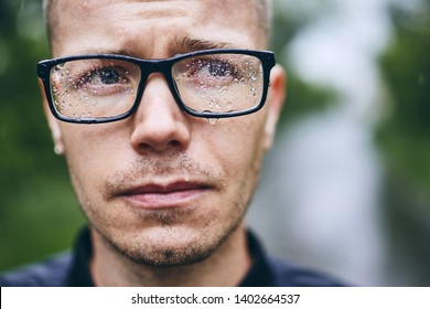 Portrait of young man with eyeglasses in rain. Selective focus on raindrops. - Powered by Shutterstock