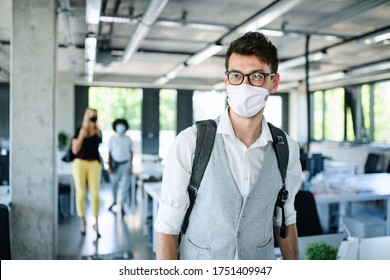Portrait of young man with face mask back at work in office after lockdown. - Shutterstock ID 1751409947