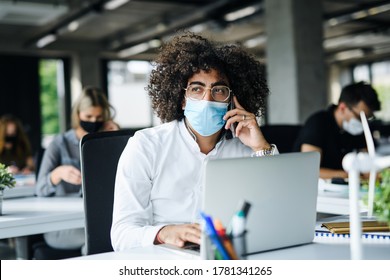 Portrait Of Young Man With Face Mask Back At Work In Office After Lockdown.