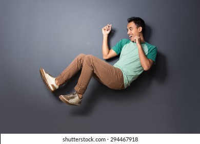 portrait of young man floating and act like fall over isolated on dark background