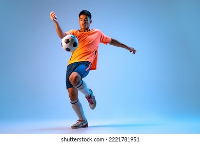 Portrait of young man, football player in motion, action, kicking ball with knee isolated over blue background in neon light. Concept of sport, team game, action, motion. Copy space for ad, poster - Powered by Shutterstock