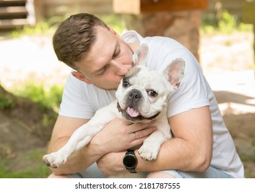 portrait of a young man with a french bulldog.young man plays teaches hugs kisses french bulldog - Powered by Shutterstock