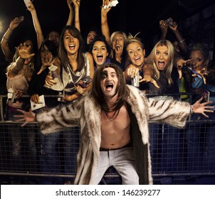 Portrait Of Young Man In Fur Coat Screaming With Excited Audience In The Background