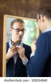 Portrait Of Young Man With Glasses Getting Ready, Dressing Up And Looking At Mirror