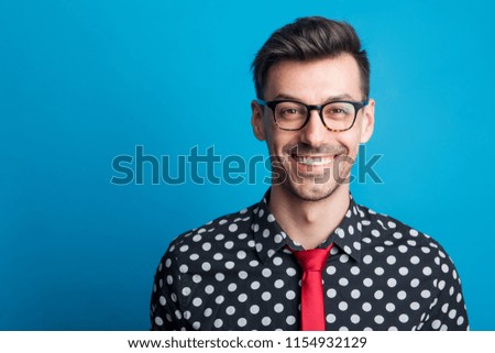Portrait of a young man with glasses in a studio on a blue background.