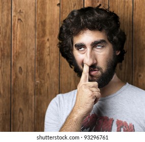portrait of a young man with his finger in his nose against a wooden wall
