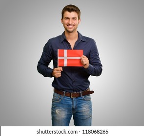 Portrait Of A Young Man Holding A Danish Flag On Grey Background