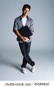 Portrait Of Young Man Holding Laptop, Studio Shot On Gray Background