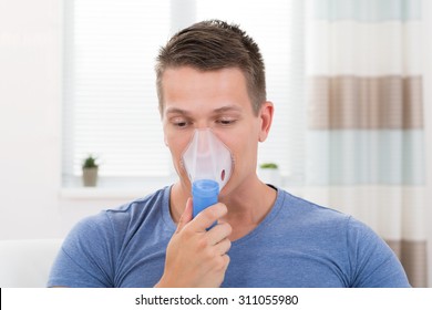 Portrait Of Young Man Inhaling Through Inhaler Mask