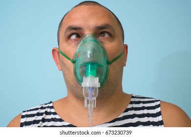 Portrait Of Young Man Inhaling Through Inhaler Mask