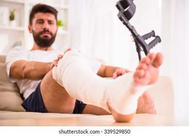 Portrait of a young man with injured leg at home