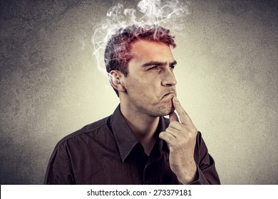  Portrait of Young man intensively thinking too hard with waving smoke from head.