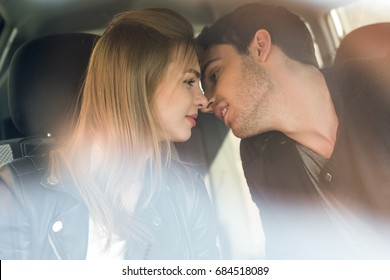 portrait of young man kissing beautiful girlfriend while sitting in car