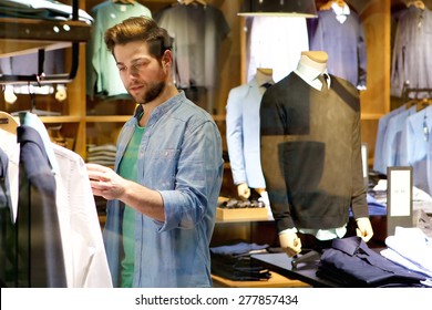 Portrait Of A Young Man Looking At Clothes To Buy At Shop