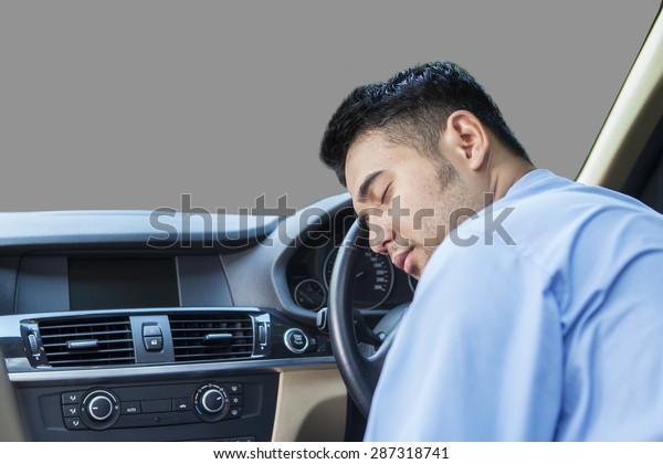 Portrait of young man looks exhausted and sleep\
in the car while\
driving