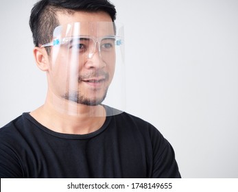 Portrait of young man in medical face shield to prevent coronavirus communicable diseases, on grey background.
