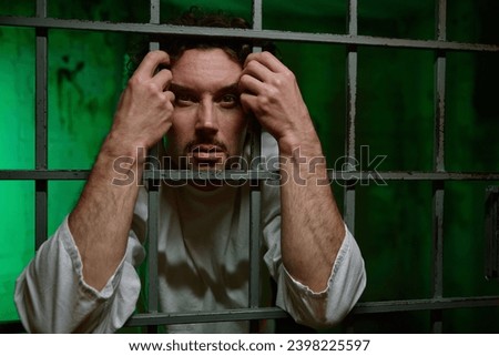 Portrait of young man with mental disorder behind cage-ward door