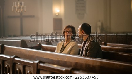 Portrait of Young Man and Old Woman Talking and Discussing While Sitting in a Church. Faithful Parishioners Seeking Comfort In Faith And Religious Beliefs, Consulting, Sharing Experiences and Wisdom