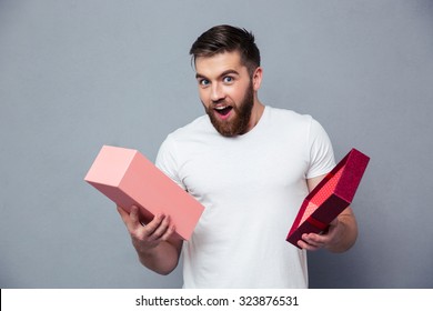 Portrait Of A Young Man Opening Gift Box Over Gray Background