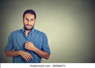 Portrait young man opening shirt to vent, it's hot, unpleasant, awkward situation, playing nervously with hands. Embarrassment. Isolated gray background. Negative emotions facial expression feeling