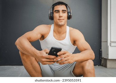 Portrait of young man outdoor use headphones and smart phone to play music or watch video podcast - Shutterstock ID 2395053591